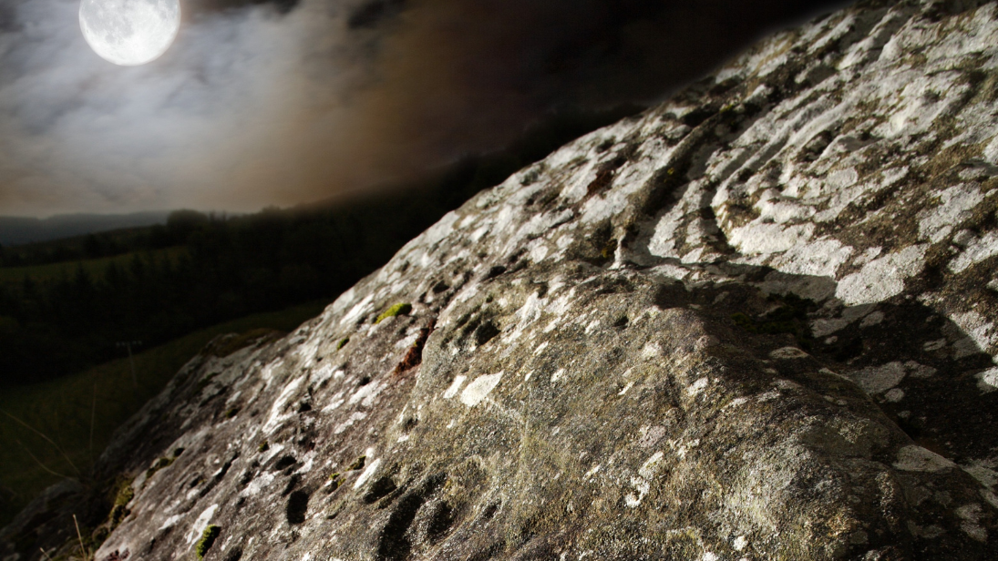 The moon casting light onto ancient rocks