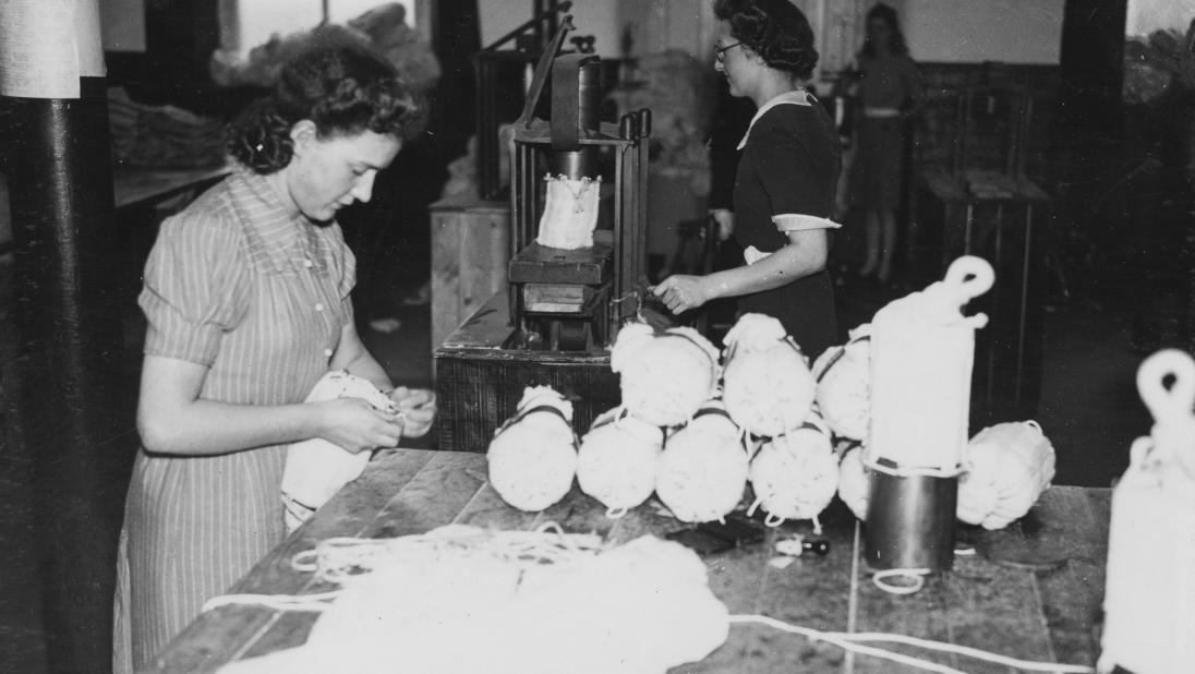 Women packing small parachutes into containers