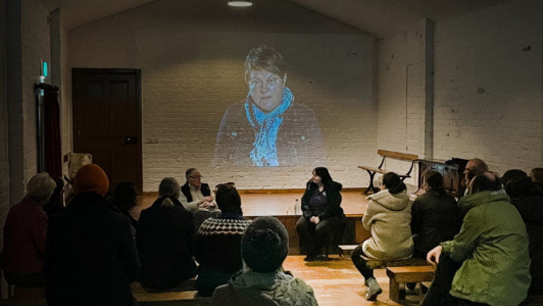 People sitting on benches inside the Picture House watching 'The Troubles I've Seen' film