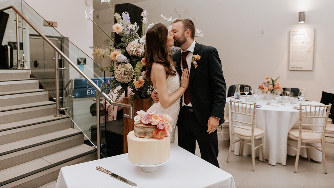 Couple kissing with their wedding cake