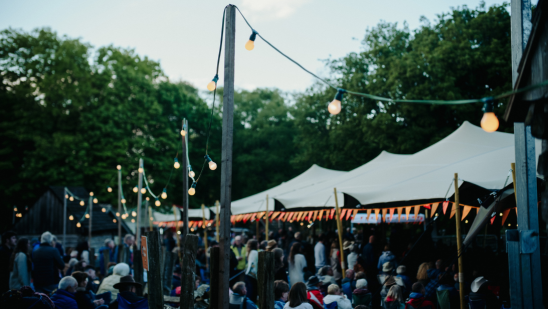 The main stage at dusk, with twinkling lights and people enjoying the music