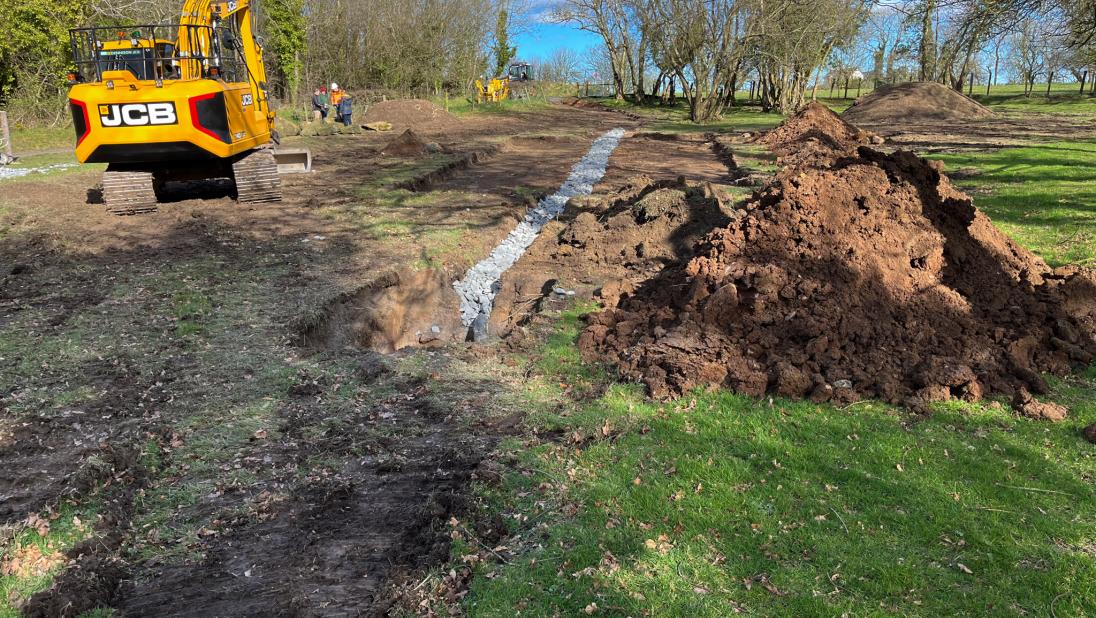 A field under construction with a digger in the background.