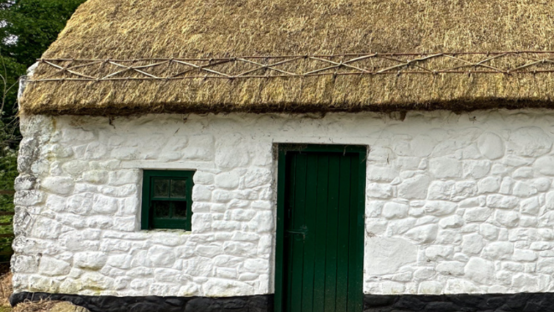 An image of a whitewashed cottage with a newly thatched roof.