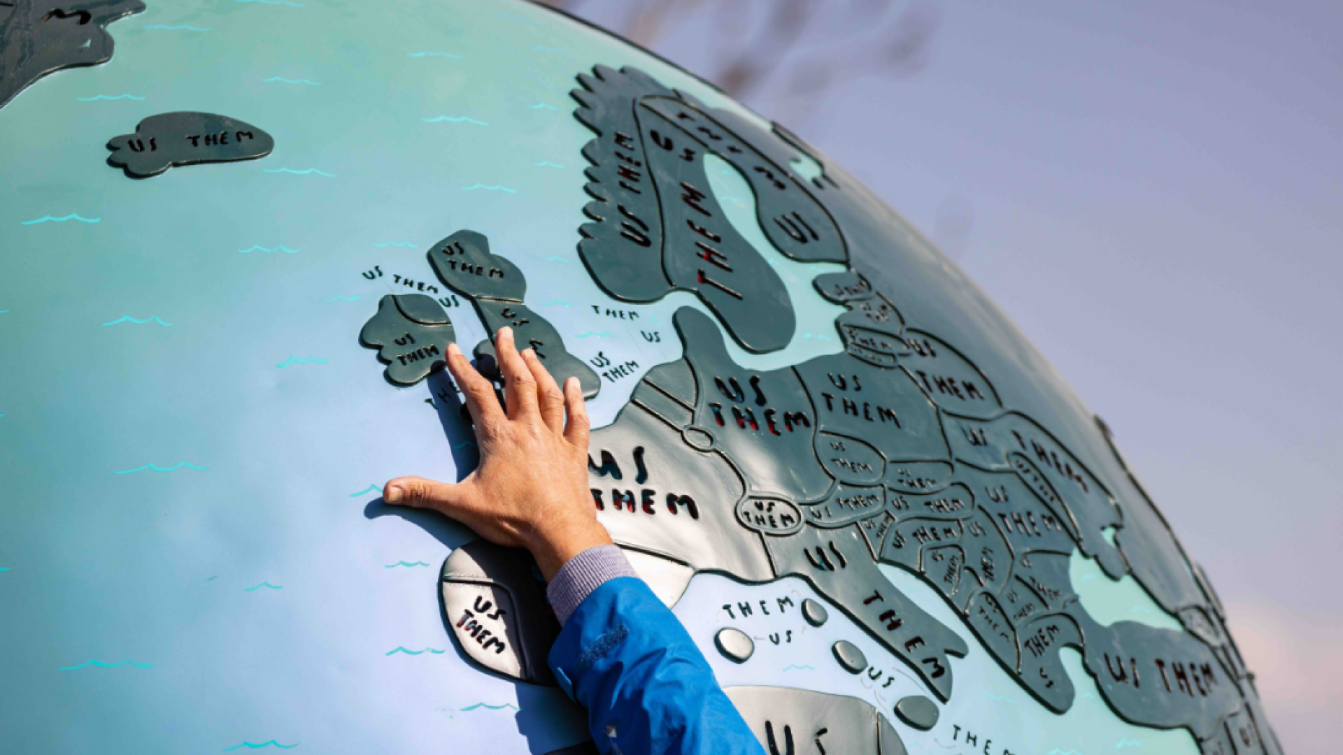 Hand pointing to Northern Ireland on globe sculpture