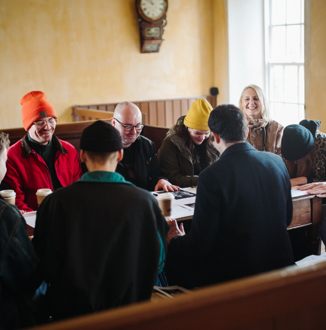 Group of people sitting around a table laughing at storytelling