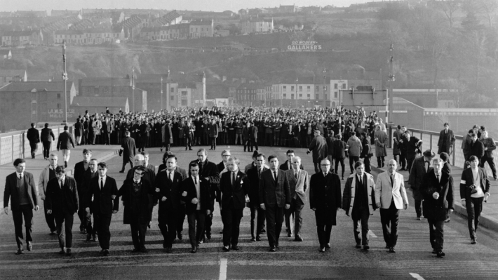 Voices 68, men walking along Craigavon Bridge