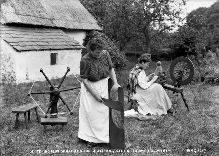 Ladies scutching flax outside