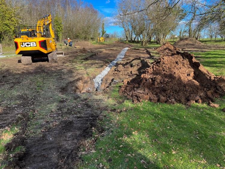 A field under construction with a digger in the background.