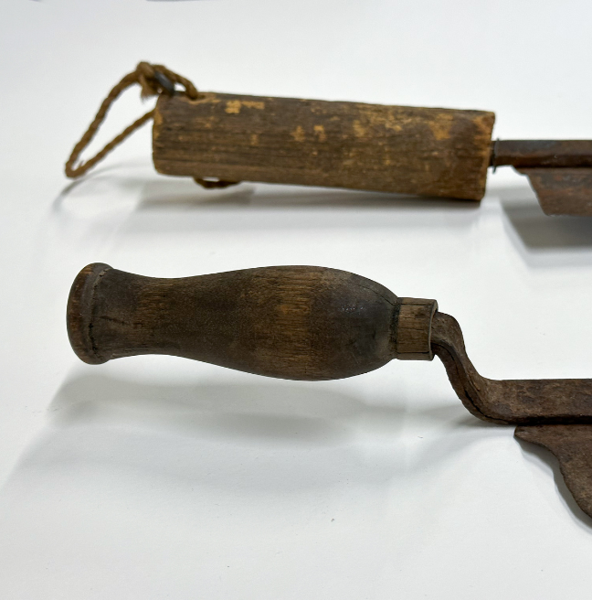 The handles of two thatching knives showing the variation of design. One is long and straight, the other shorter and curved.