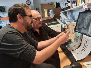 Two men study a computer rendering of a Neolithic court tomb