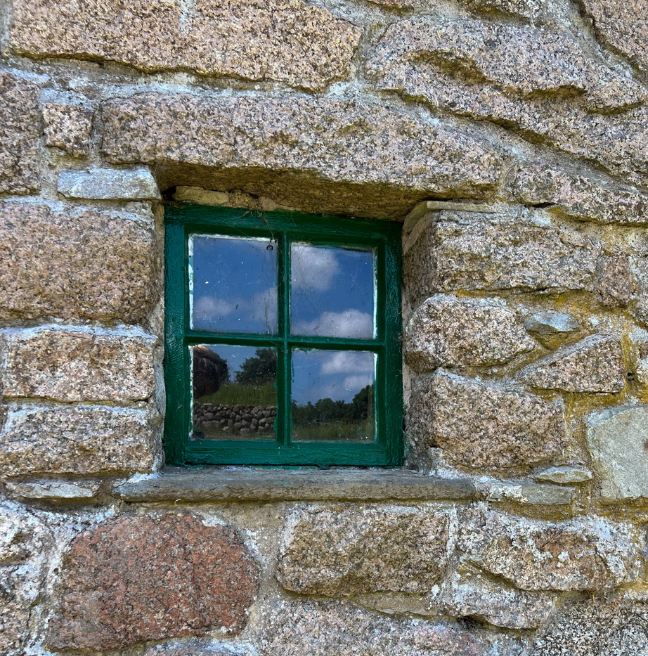 A close-up of a green window in a stone wall.