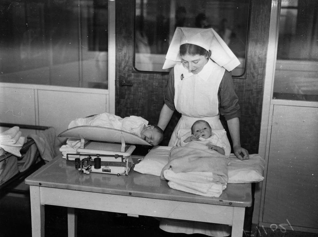 Nurse weighing babies